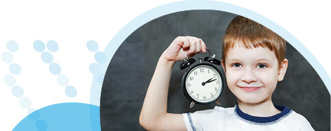 ילד מחייך מחזיק שעון מעורר ביד ימין ליד הראש