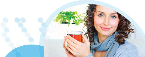 אישה לבושה צעיף מחזיקה כוס תה בשתי ידיה