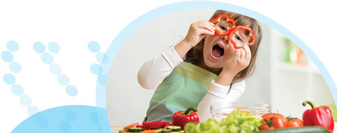 ילדה מכסה את עיניה עם טבעות פלפל אדום ומסביבה ירקות