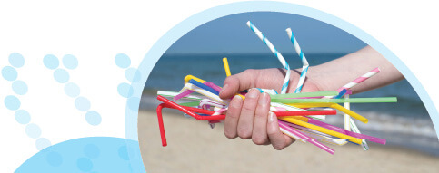 יד מחזיקה קשיות פלסטיק צבעוניות על רקע חוף ים