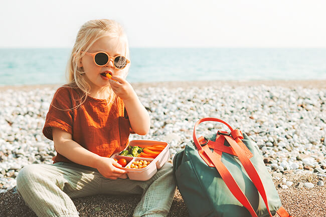 ילדה אוכל בחוף ים קיץ